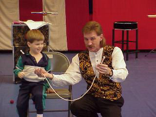 Magician Rodney Kelley performing cut and restored rope with boy volunteer